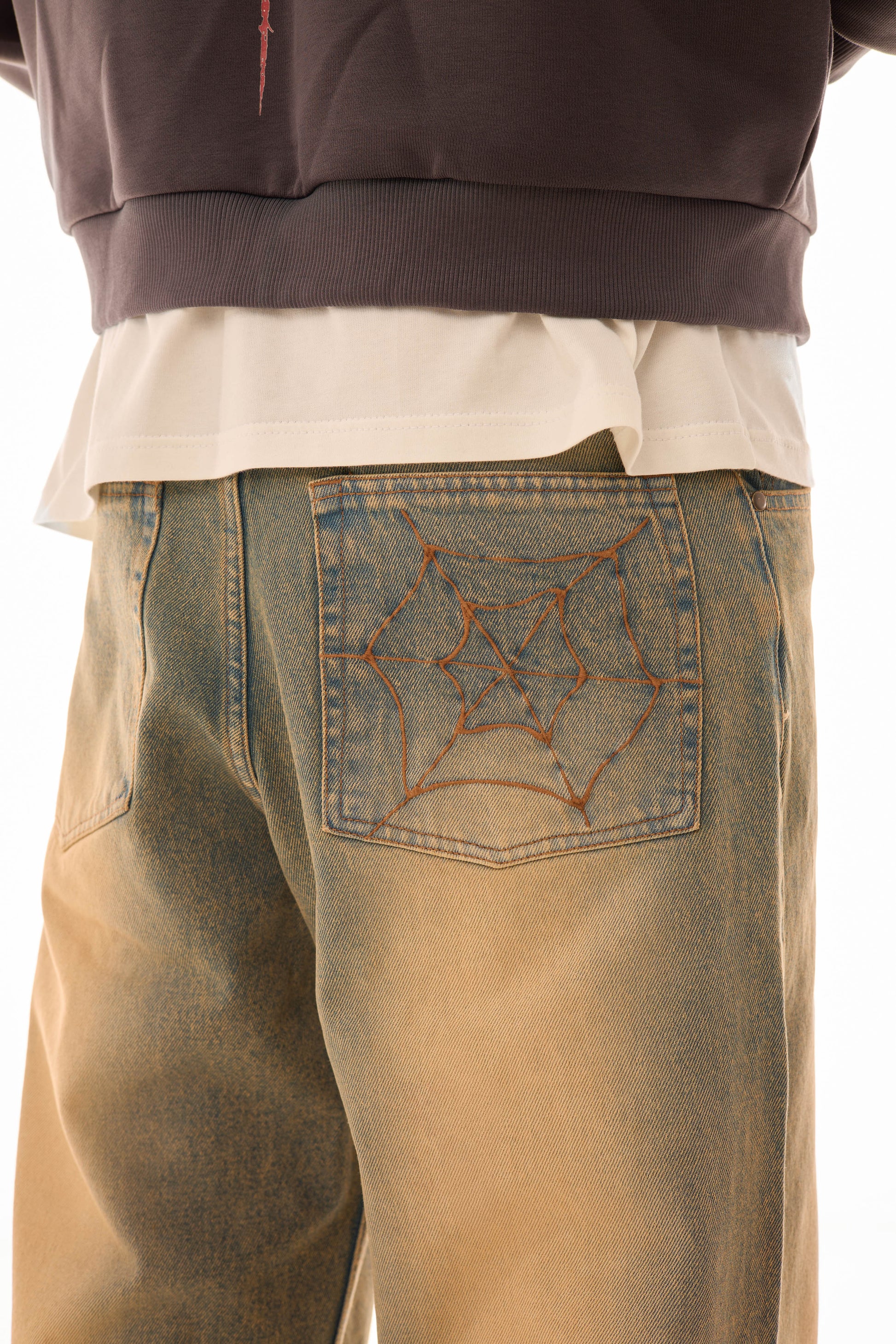 Detaliu buzunar spate al blugilor wide-leg albaștri cu efect stonewash și broderie model pânză de păianjen