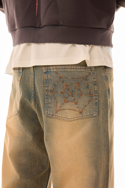 Detaliu buzunar spate al blugilor wide-leg albaștri cu efect stonewash și broderie model pânză de păianjen