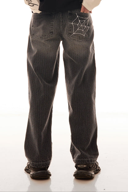 Close-up din spate cu blugii Axis Denim gri, wide fit, cu tighele verticale albe și broderie pe buzunarul spate.
