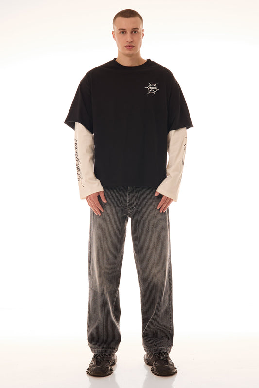 Model purtând blugii Axis Denim gri, wide fit, cu tighele verticale albe și fading subtil, integrați într-un outfit streetwear.
