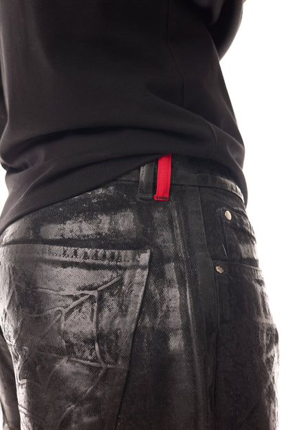 Detaliu close-up al blugilor Midnight Denim, cu coating cerat pe bază de silicon, buclă roșie la betelie și buzunar spate texturat.
